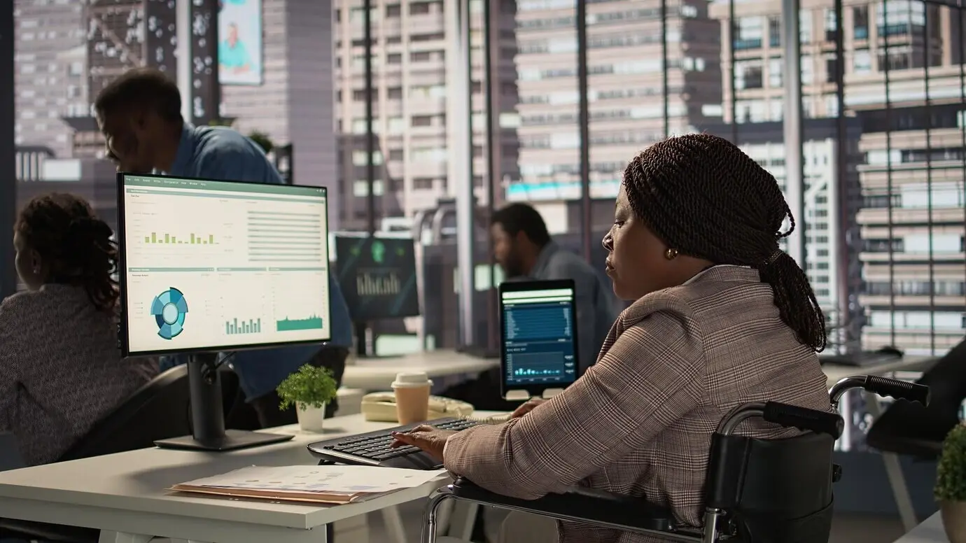 Женщина-руководитель с хронической инвалидностью изучает архивные файлы и отчеты с данными.